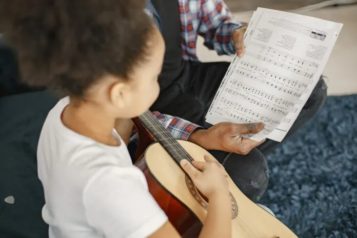 pai-com-filha-no-sofa-menina-segurando-uma-guitarra-aprendendo-violao_1157-47340-696x464